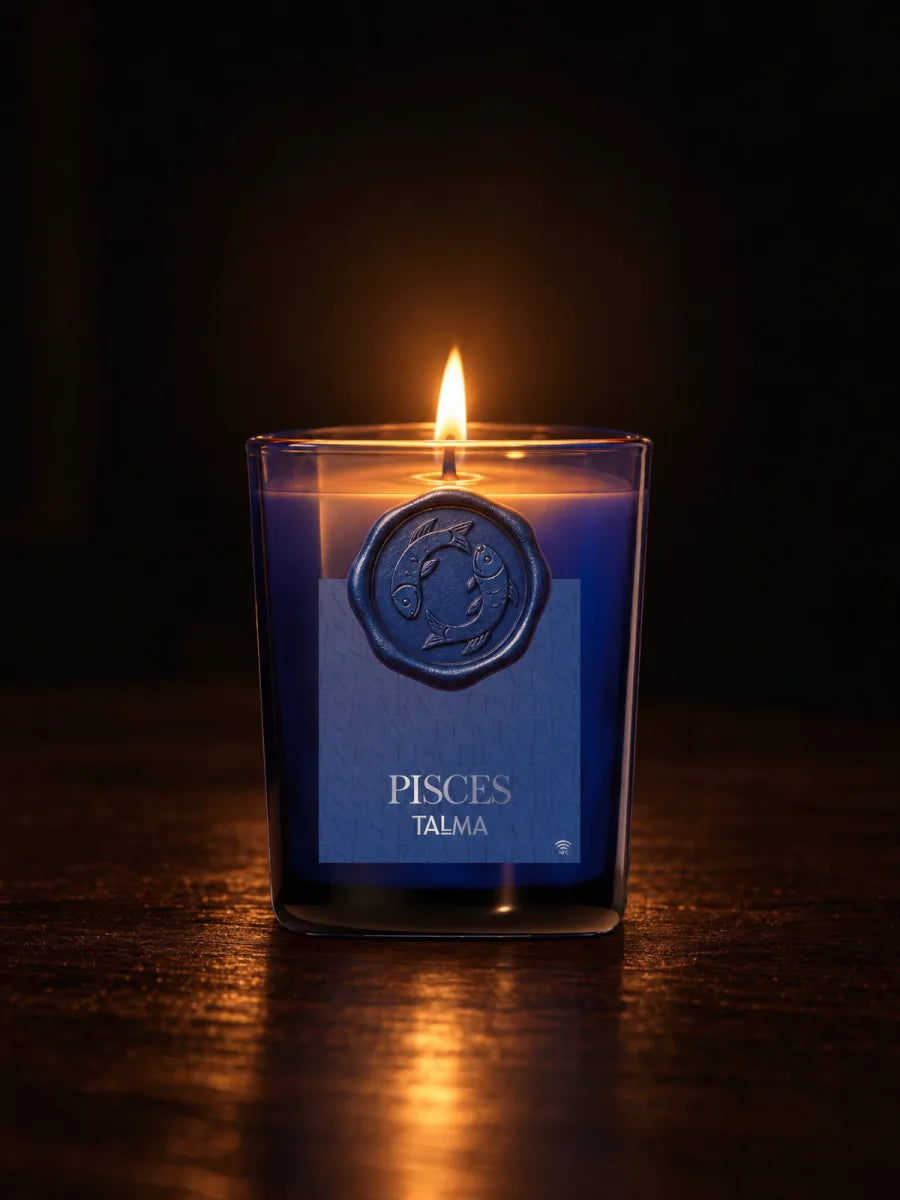 The Pisces candle lit in the dark, its wax seal on the blue glass.