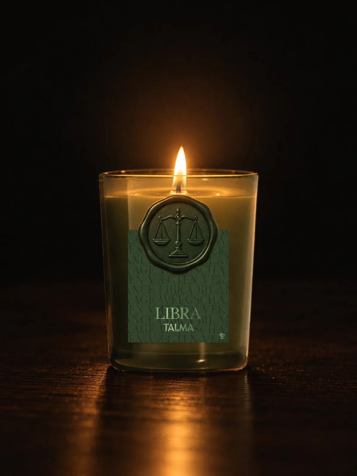 The Libra candle lit in the night, green glass