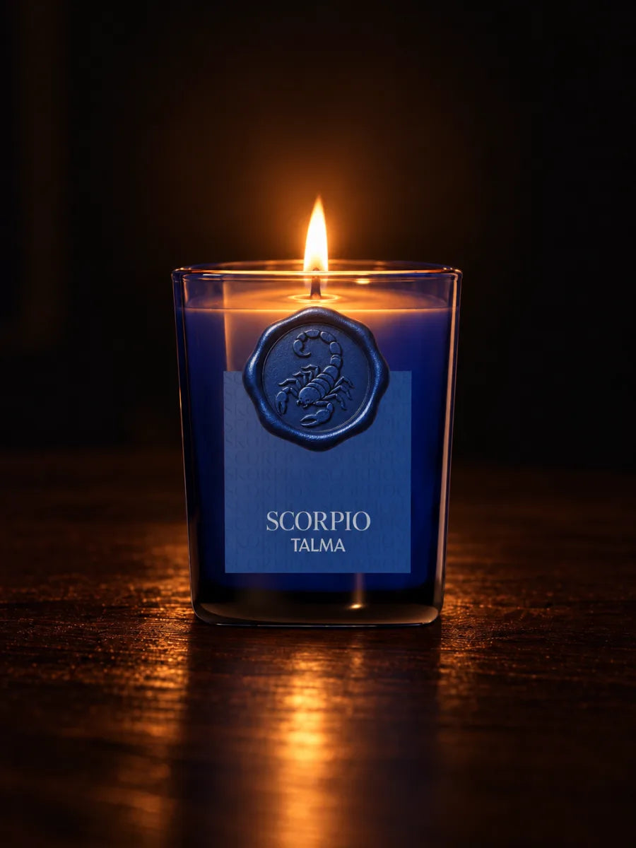 The Scorpio candle lit in the dark, its wax seal on the blue glass.